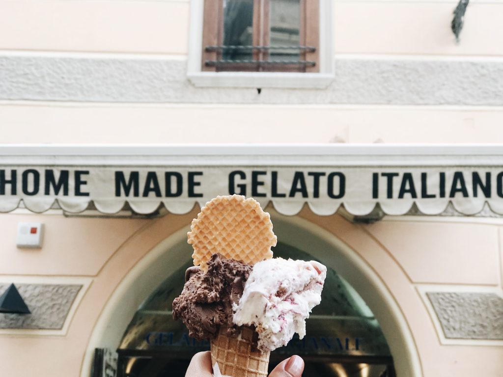 hand holding a cone of homemade gelato in front of the gelato store front in Amalfi Coast, Italy